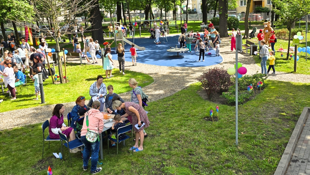 Obchody Dnia Dziecka w parku przyszpitalnym – pacjenci i opiekunowie przy stoiskach z atrakcjami, dzieci na placu zabaw